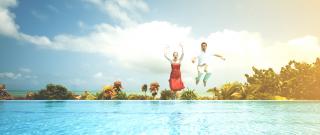 Two people jumping into a pool