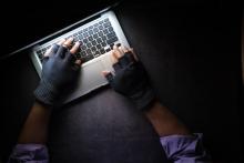 hacker in fingerless gloves plies his trade